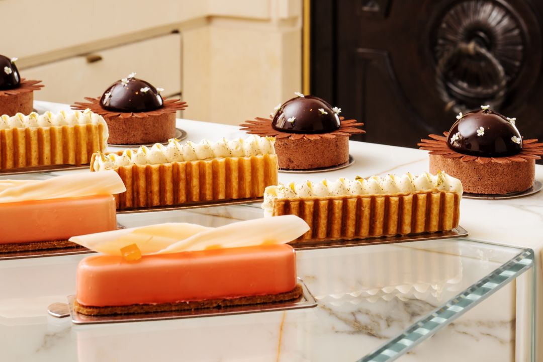 Assorted pastries and desserts in a glass case and on a stand from a pâtisserie in Paris.